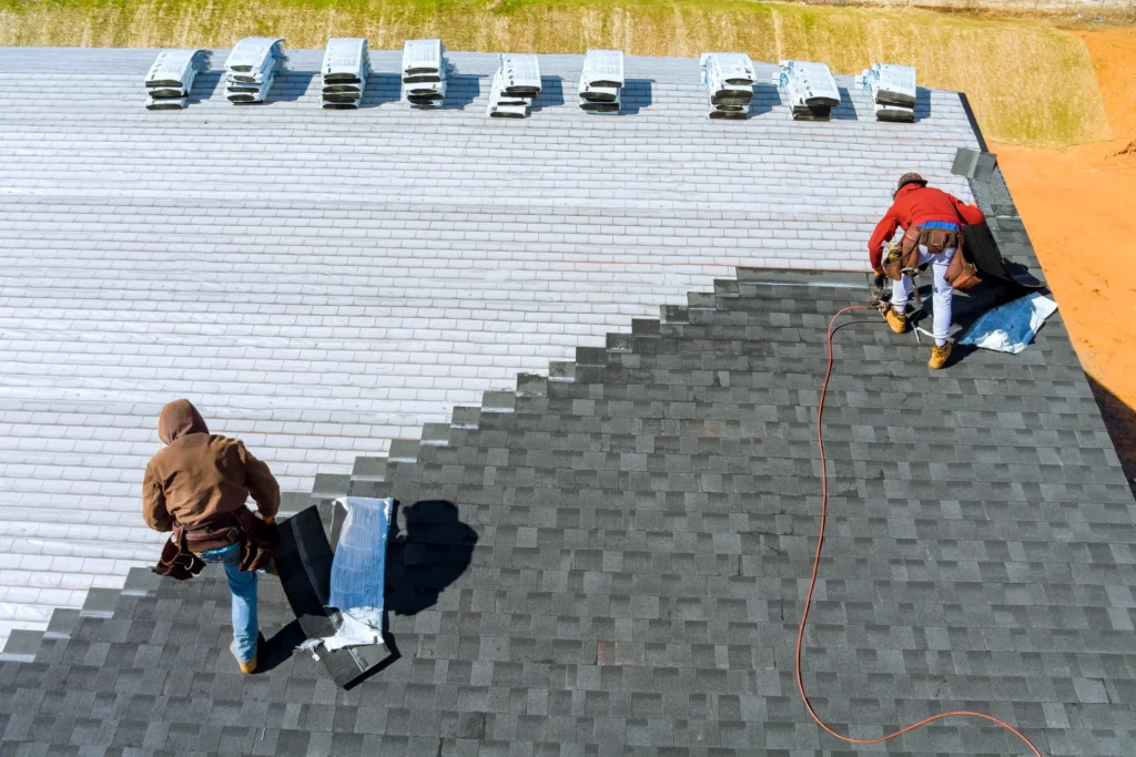 Roofing crew aligning shingles during shingle roof installation to ensure straight rows and proper overlapping.